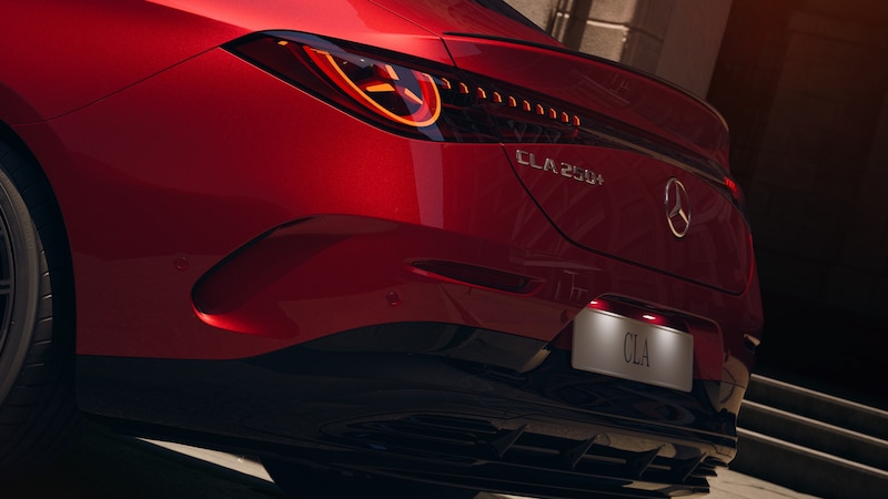 Der rote Mercedes-Benz CLA Elektrisch ist von hinten mit beleuchteten Rückleuchten, Sternemblem und aerodynamisch geformtem Heckstoßfänger zu sehen.
