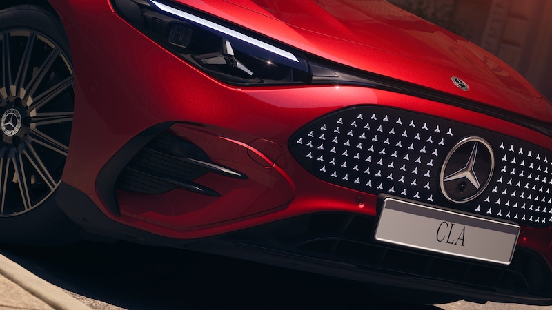 Roter Mercedes-Benz CLA Elektrisch mit beleuchtet wirkendem Sternmuster im Kühlergrill, LED-Scheinwerfer und sichtbarem Vorderrad.