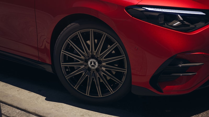 Ein roter Mercedes-Benz CLA Elektrisch ist im Detail mit Vorderrad, mehrspeichiger Felge und schmalem LED-Scheinwerfer zu sehen.