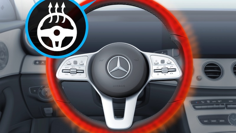 Das Mercedes-Benz Lenkrad ist mit Bedienelementen und einem roten Wärmeeffekt dargestellt, der die Lenkradheizung für kalte Tage veranschaulicht.