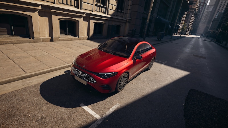 Ein roter Mercedes-Benz CLA Elektrisch steht auf einer sonnigen Stadtstraße und zeigt seine markante Front, flache Silhouette und dunklen Räder.