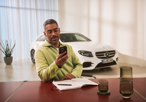 Economies | Mercedes-Benz Un consultant assis à une table et regardant son smartphone.