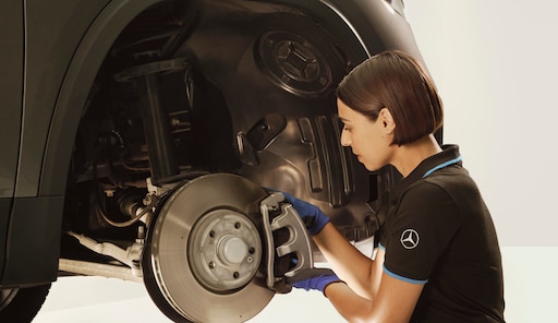 Freins | Mercedes-Benz Un technicien réparant les freins d'un véhicule Mercedes-Benz.