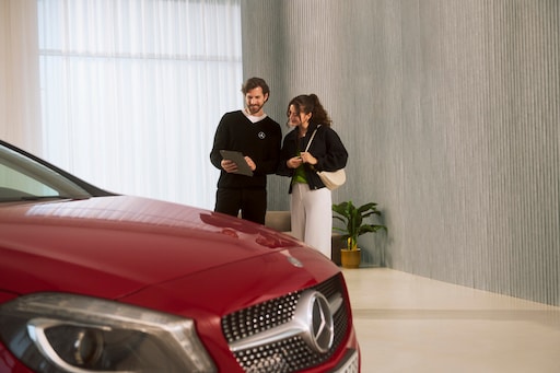 Services de maintenance | Mercedes-Benz Un conseiller se tenant à côté d'un véhicule et échangeant avec un client.