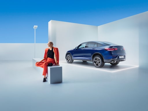 Une femme se détend sur un banc devant sa Mercedes-Benz.