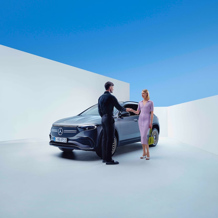 Un employé de Mercedes-Benz et une femme se serrent la main devant une Mercedes-Benz
