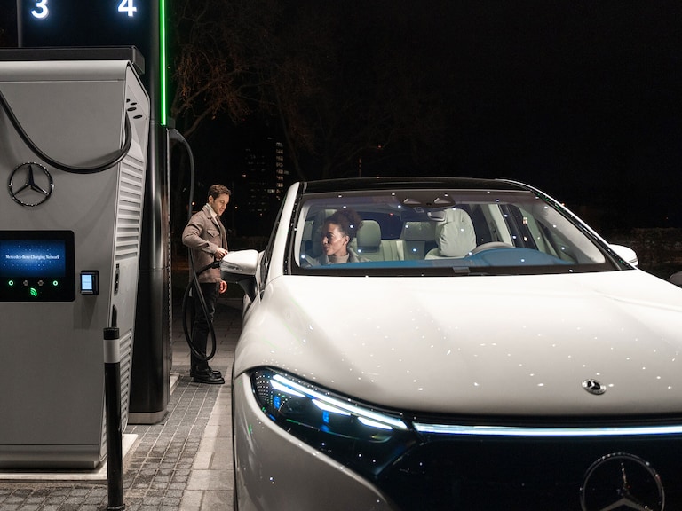 Charging solutions | Technology | Mercedes-Benz The Mercedes-Benz CLA standing on a street, connected to a charging station.