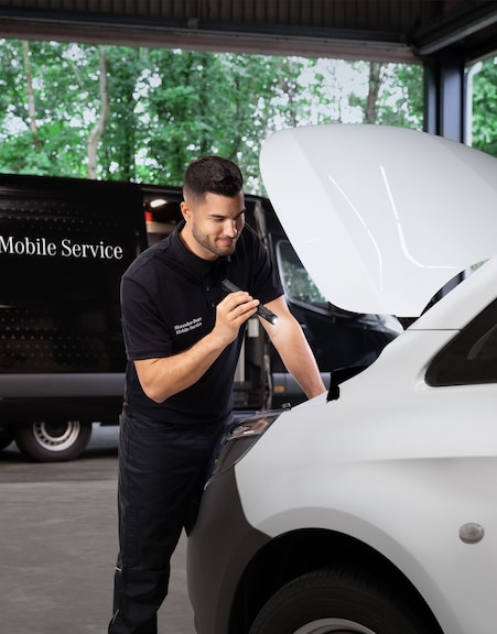 Mercedes-Benz | Wartung | Mobile Service Mechaniker bei der Inspektion des Motors eines weißen Mercedes-Benz Transporters.